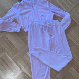 Rosa hoodie och byxor set - Säljer ett mysigt rosa set med hoodie och matchande byxor. Hoodien har dragkedja och långa ärmar, perfekt för en avslappnad dag. Byxorna har en bekväm passform med resår i midjan och dragsko. Perfekt för hemmamys eller en lugn promenad.