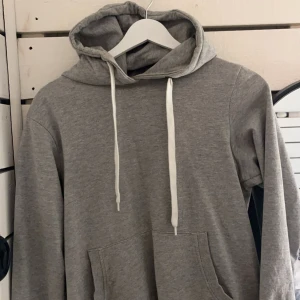 Grå hoodie med ficka - Säljer denna hoodie för att den aldrig kommer till användning, super bekväm och har tjocka snören som gör hoodien blir snyggare. 