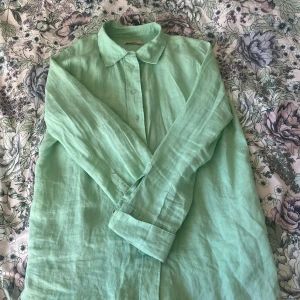Mintgrön linneskjorta från Gina Tricot - Säljer en fräsch mintgrön skjorta i linne från Gina Tricot. Skjortan har långa ärmar och knappar framtill. Perfekt för en stilren och bekväm look. Knappt använd! Finns hund och katt i hemmet, tvättas innan den skickas!