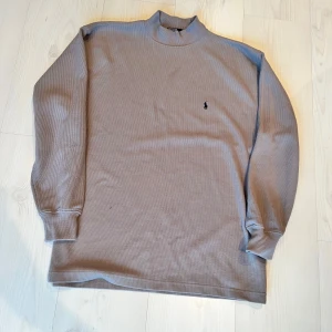 Beige långärmad tröja från Polo Ralph Lauren - Säljer en stilren beige långärmad tröja från Polo Ralph Lauren. Tröjan har en broderad logotyp på bröstet och en ribbad krage. Perfekt för en avslappnad och klassisk look. Läger som L för den passar L 