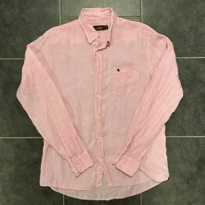 Rosa skjorta från Morris - Snygg rosa skjorta från Morris i storlek L. Skjortan har en klassisk krage och knappar framtill. Perfekt för en stilren look. (100% linen)