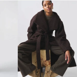 Mörkbrun kappa med bälte - Säljer en supermysig mörkbrun kappa med bälte. Den är lång och perfekt för höst och vinter. Kappan har en loose passform och är gjord i ett mjukt material som känns som en dröm att ha på sig. Perfekt för att hålla sig varm och stilren samtidigt!