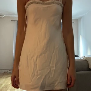 Vit axelbandslös klänning - Säljer en superfin vit axelbandslös klänning i kort modell. Perfekt för sommarens fester! Klänningen har en smickrande passform och är gjord i ett glansigt material som ger en lyxig känsla. Den har en dragkedja på sidan för enkel påklädning. Passar perfekt för en kväll ute eller en speciell tillställning.