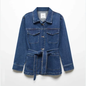 Blå jeansjacka med bälte - Säljer en snygg blå jeansjacka från mango som är helt slutsåld överallt. Normal passform. Jackan har långa ärmar och ett bälte i midjan för en cool look och figursydd effekt. Perfekt för vår och höst! Den har knappar framtill och två bröstfickor. En klassisk stil som funkar till det mesta. 