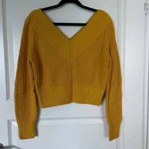 Gul stickad tröja med v-ringning - Säljer en superfin gul stickad tröja med v-ringning. Den är croppad och har långa ärmar med ribbade detaljer vid ärmslut och nederkant. Perfekt för höst och vår när du vill vara både stilren och bekväm. Passar perfekt till jeans eller kjol!