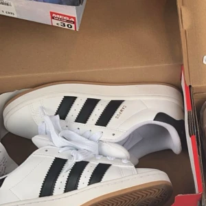Adidas Campus 00’s - Säljer ett par snygga Adidas Campus 00’s  i vitt med svarta ränder. strl 37,5. Använda fåtal ggr pga för liten strl för mig, därför jag säljer.