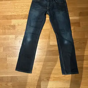 Säljer ett par mörkblå jeans från Jack & Jones i modellen Tim. De är i bra skick och har en klassisk straight passform. Perfekta för både vardag och fest. Tillverkade i Italien med en snygg tvätt som ger en använd look. Priset kan diskuteras om