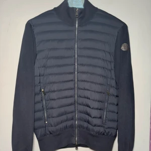 Moncler cardigan  - Säljer en snygg marinblå cardigan från Moncler i bra skick. Storlek L sitter som M. Som man ser på sista bilden så är det lite sönder vid ena armen, men syns knappt när den är på. Därav lite billigare pris. Perfekt för höst och vår. Äkta såklart. Pris kan diskuteras vid snabb affär. 