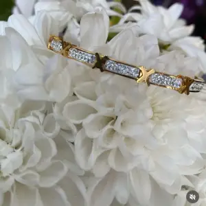 Ett elegant rostfritt stål guld färg armband med stjärnformade detaljer och glittrande stenar. Perfekt för att ge en touch av glamour till vilken outfit som helst. Armbandet har en stilren design med en rad av små stenar infattade mellan stjärnorna. Passar både till vardags och festliga tillfällen.