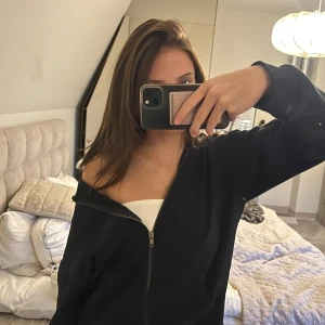 Svart hoodie med dragkedja - Säljer en svart hoodie i mycket bra skick. Den har en dragkedja framtill och en skön luva. Perfekt för höst och vinter, och passar till både chill och vardagsoutfits. Storleken är normal och materialet känns mjukt och bekvämt. Använde för ungefär ett år sedan lite då och då, men är fortfarande i bra skick utan några slitningar.