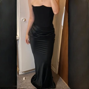 Svart axelbandslös klänning från House of CB - Klänning ifrån House of CB, använd endast vid ett tillfälle. Den har även kvar prislappen. Klänningen har en inbyggd korsett med en mindre storlek i bysten (A/B cup) och klänningen är i storlek XS. Nypris är 288€ vilket motsvarar ungefär 3450kr. Priset kan diskuteras!🩷