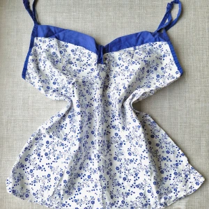 Vintagelinne - Suppergulligt vintagelinne 🌸 I mycket fint skick! Vitt med blå blommor och kant. Justerbara axelband. Av okänt märke. Säljer då det är för stort för mig, passar nog bäst på L. (Mått kan såklart fås vid intresse!) Öppen för prisförslag :)