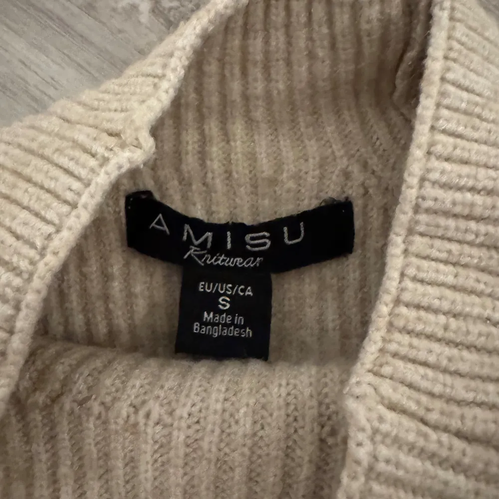 Mysig beige stickad tröja från Amisu i storlek S. Perfekt för kyliga dagar med sin ribbade design och långa ärmar. Tröjan har en klassisk look som passar både till vardags och lite finare tillfällen. Superbekväm och lätt att matcha med andra plagg!. Neuletakit & Villapaidat.