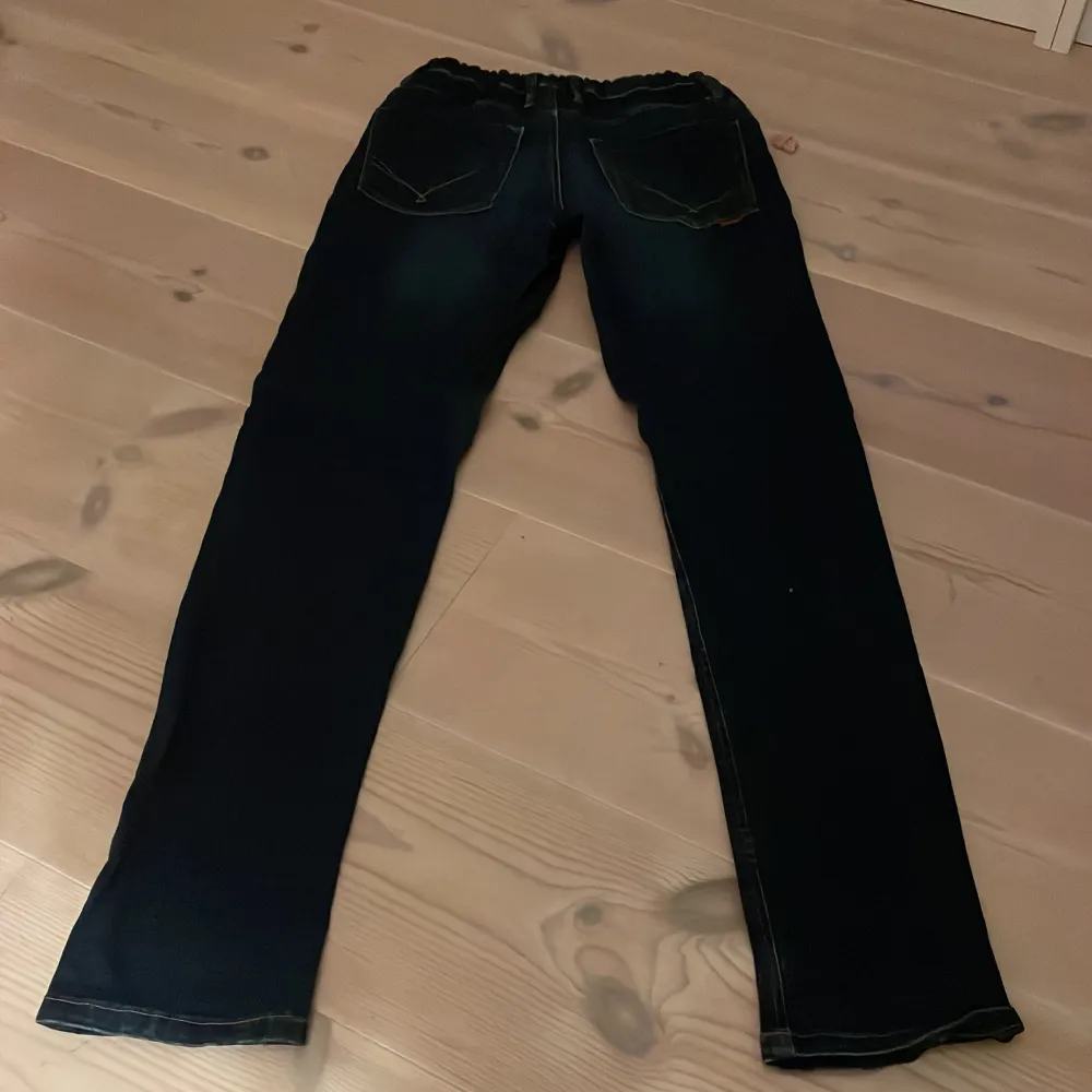 Säljer ett par mörkblå jeans från Name It i storlek 164. De har en klassisk straight passform och är perfekta för vardagsbruk. Jeansen är i bra skick och har en snygg tvätt som ger dem en cool look. Perfekta för både skola och fritid!. Jeans & Byxor.