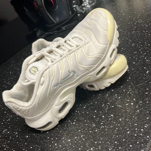 Vita Nike Tn skor  - Säljer ett par vita Nike Air sneakers i bra skick. De har en snygg och futuristisk design med synlig Air-dämpning i sulan. Perfekta för både vardag och träning. Lite gulnad på tån men annars i fint skick. Passar perfekt för dig som gillar stilrena och bekväma skor.