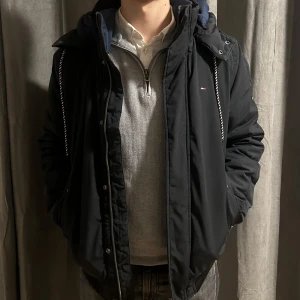 Svart vinterjacka från Tommy Hilfiger - Säljer en svart jacka från Tommy Hilfiger i mycket bra skick. Den är en limited edition och såldes för 3499kr. Den har en praktisk huva och dragkedja framtill. Perfekt för höst och vinter med sin stilrena design och bekväma passform. Jackan har långa ärmar och är gjord i ett slitstarkt material.