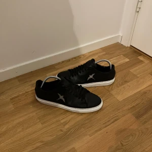 Axel Arigato Skor - Säljer ett par stilrena svarta sneakers med vit sula. De har en snygg fågeldetalj på sidan och klassisk snörning. Perfekta för vardagsbruk och passar till nästan allt. Skorna är i bra skick och redo för nya äventyr
