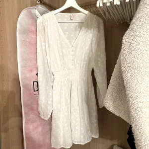 Vit blommig klänning - Säljer min studentklänning från Nelly. Klänningen är i bra skick. Passar vid olika tillfällen🤍 köpt för 499kr säljer för 250kr. Pris kan diskuteras 🤍
