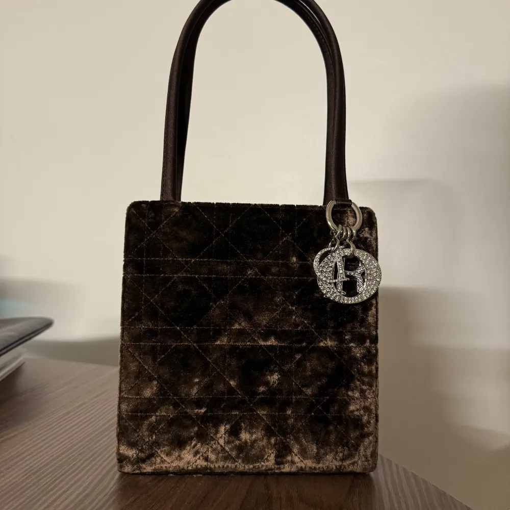 Dior väska i en mörkare brun färg i sammet med silver detaljer. Väskan är i mycket bra nästan oanvänt skick. Väskan saknar äkthetsbevis och låda/dustbag då jag fick den av en släkting som inte fick någon användning av den.. Väskor.