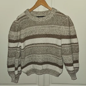 Stickad tröja nytt  - Nytt Snygg randig tröja med puffärmar och trekvartsärm. Tröjan är i en härlig färgkombination med beige ,vitt och brunt Nypris 500 kr