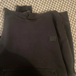 Acne studios hoodie - Svart hoodie från Acne studios ur gamla ferris face kollektionen. Tyvärr har hoodie blivit för liten för min del…  Storlek M  Tyvärr har sömmen släppt lite vid handlederna men inga problem att sätta ett par stygn så är det löst:)
