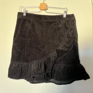 Svart kjol - Svart räfflad kjol i sammet med dragkedja i sidan, köpt på Bik Bok för 3 år sedan, använd 1 gång - nyskick. Lappen där bak är bortklippt men kjolen är i storlek 44, midjemått: 84 cm