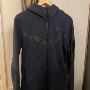 Nike tech - Snygg Nike tech i helt okej skick 6/10. Väldigt lite nopprig på magen och har någon sorts Olje fläck på under armen (syns på bild 3) syns egentligen inte så mycket i verkligheten, syns bara extra för bilden är tagen med blixt. Kommer bilder privat. Liten rivning i fickan, synd på sista bild