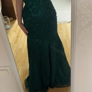 Balklänning  - Fin balklänning, använd en gång. Mörk grön fin balklänning med ett litet släp. Jag har vanligtvis S eller M, 167 cm lång och den satt perfekt. Går att justera!! Hör av er om ni har frågor!