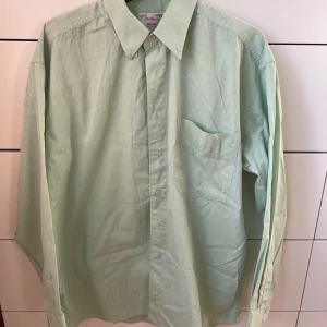 Ljusgrön skjorta från Melka - Säljer en klassisk ljusgrön skjorta från Melka. Den har en stilren design med långa ärmar och en bröstficka. Perfekt för både vardag och lite finare tillfällen. Skjortan är i bra skick och redo för en ny ägare!😀