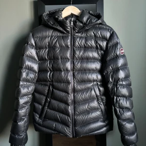 Colmar dunjacka - Mörkgrå, glansig Colmar dunjacka. Har tyvärr ”fläckar” från att det regnat på den, märks dock inte i alla ljus. Pyttelitet hål på framsidan. I övrigt bra skick. Storlek 46 men passar bra på S/M