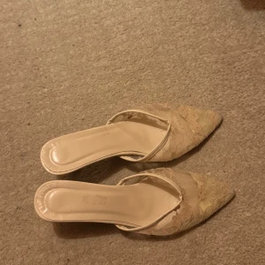 Beige spetsiga klackskor - Säljer ett par eleganta beige klackskor med spetsig tå och spetsdetaljer. Skorna har en smal klack och är perfekta för en stilren look. Är köpt second hand, säljes i befintlig sick 