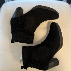 Svarta boots med klack - Snygga svarta mockastövletter i mocka med klack, liten platå och dragkedja. De har en elegant textur på skaftet och en robust sula. Perfekta för att ge en stilren touch till din outfit.