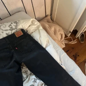 Superlow bootcut levis - Snygga svarta jeans från Levi's med klassisk design och fem fickor. Perfekta för en stilren look. De har en knappgylf och är tillverkade i slitstarkt denim. Modellen är superlow bootcut.