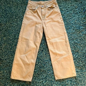 Gula Jeans  - Gula, vida jeans med en avslappnad passform. Från monki. Byxorna har en klassisk design med fickor och knappstängning. De är använda, men har endast en liten fläck vid knät (se bild 2).