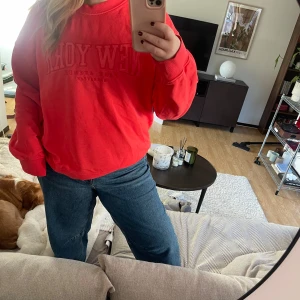 Röd sweatshirt  - Säljer en cool röd sweatshirt med tryck framtill. Tröjan har en avslappnad passform och långa ärmar, perfekt för en casual look. Passar bra till jeans eller leggings.