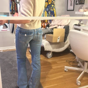 Blå bootcut jeans - Snygga blå bootcut jeans med klassisk femficksdesign och knappdetaljer på bakfickorna. Perfekta för en avslappnad stil.