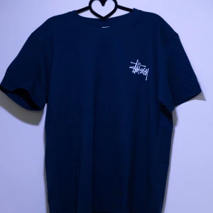 Mörkblå t-shirt från Stüssy - Relativ ny mörkblå t-shirt från Stüssy med deras ikoniska logga i vitt på både fram- och baksidan. Perfekt för en avslappnad stil. Kom med frågor och bud!😊