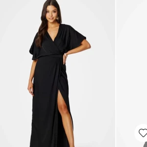 Svart långklänning från Bubbleroom - Elegant svart långklänning från Bubbleroom med v-ringad design och slits. Klänningen har kortärmade och ett knytband i ryggen för extra detalj. Perfekt för speciella tillfällen. Har den i storlek 38 och 42!! Helt ny med ordinarie pris på 1000kr