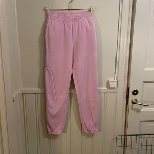 Rosa mjukisbyxor från H&M - Säljer ett par ljusrosa mjukisbyxor från H&M i storlek XS. Byxorna har en elastisk midja. Perfekta för en avslappnad stil.