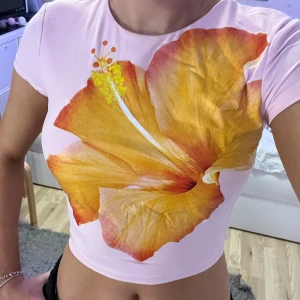 Rosa croppad topp med blommönster från Zara - Säljer en rosa croppad topp från Zara med ett stort, färgglatt blommönster i gult och orange. Ej använd en enda gång. Om du har några frågor, vänligen kontakta mig på engelska.🥰🥰