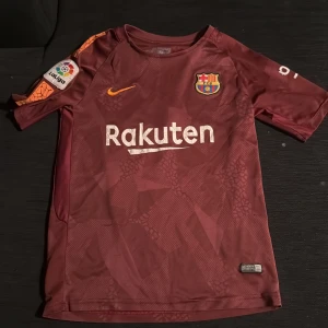 Vinröd FC Barcelona fotbollströja - Säljer en vinröd FC Barcelona fotbollströja från Nike med Messi 10 på ryggen. S i barnstorlek