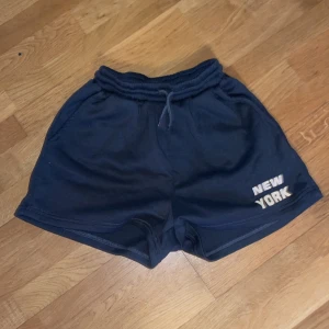 shorts med texten 'New York' - Snygga shorts från SHEIN med texten 'New York' tryckt på ena benet. De har en elastisk midja med dragsko för justerbar passform. Perfekta för en avslappnad stil.