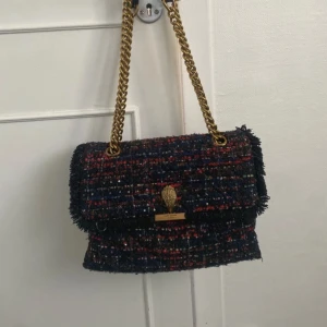 Flerfärgad axelväska från Kurt Geiger - Säljer min jättesnygga och coola Kurt Geiger väska med gulddetaljer i en mellanstor storlek. Köpt för ca 2800 kronor. Den är lite nopprig på vissa ställen, speciellt på baksidan (se bild 3) men det är inget man ser tydligt. Annars fint skick! Så rymlig väska med tre inre fack. Pris kan diskuteras!