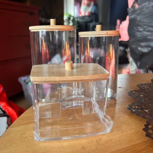Förvaringsset för badrummet! - Stilrent förvaringsset i genomskinlig plast och lock i ljust trä för t ex bomullspinnar, bomullsrondeller och andra småsaker. Burkarna är 7, 11 & 12 cm höga. Nya!