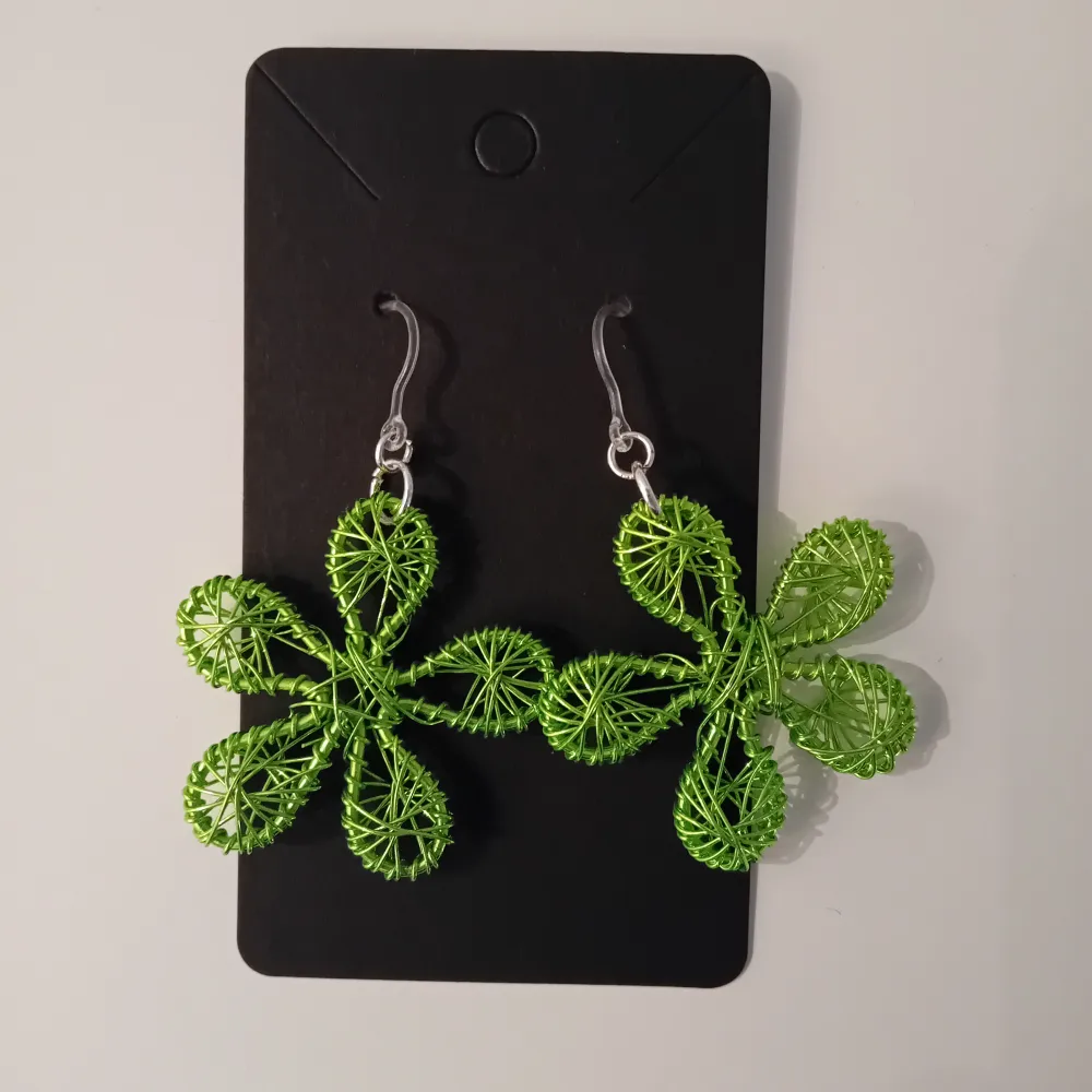 Egentillverkade gröna örhängen formade som blommor. Öronkroken är gjord i plast och längden på örhängena är ca 4 cm långa.. Asusteet.