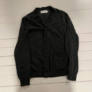 Mörkgrå kofta med knappar - Säljer en stilren mörkgrå kofta med knappar framtill och två praktiska fickor. Perfekt för kyligare dagar och enkel att matcha med olika outfits.