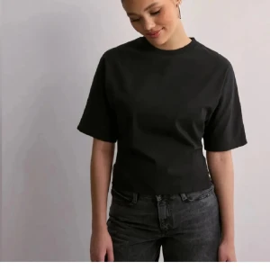 Svart kortärmad topp med knyt - Snygg svart topp med korta ärmar och knytning i ryggen. Perfekt för en stilren look.