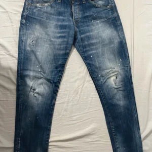 Blå jeans från Jack & Jones - Snygga blå jeans från Jack & Jones med en cool slitning och färgstänk för en avslappnad look. Modellen är slim fit och heter Glenn. Perfekta för en casual stil. Använda men varsamt. Storlek 30/30. Kan gå med på nån deal, skicka iväg ett pris/fråga!