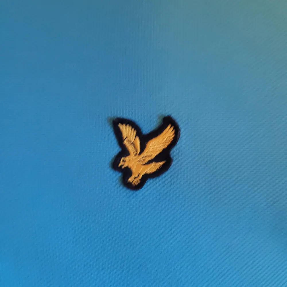 Snygg turkos pikétröja från Lyle & Scott i 100% bomull. Tröjan har en klassisk krage med knappar och det ikoniska broderade logotypmärket på bröstet. Tröjan är i en unik färg.. Neuletakit & Villapaidat.
