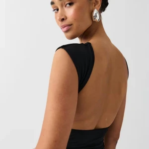 Svart topp med öppen rygg - Elegant svart topp med en djup öppen rygg och korta ärmar. Köpt från Gina tricot, använt ett fåtal gånger. 